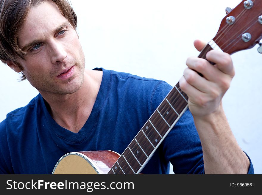 An attractive guitar player with a blue shirt and white backround