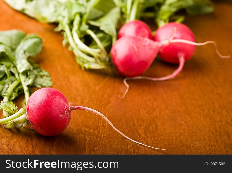 Radish on a wood cutting board leaves and roots