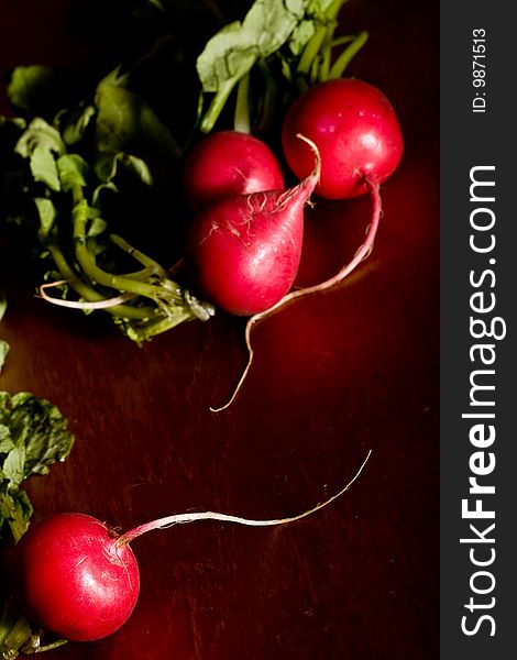 Radish on a wood cutting board leaves and roots