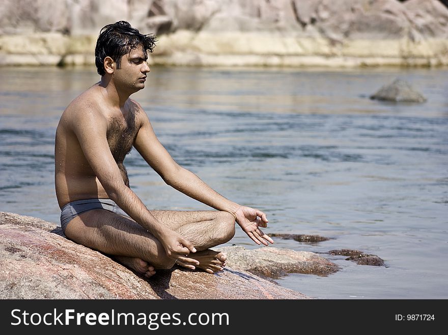 Man having yoga in water between stones