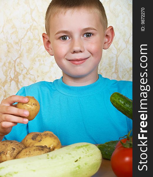 The boy sits at a table with vegetables. The boy sits at a table with vegetables