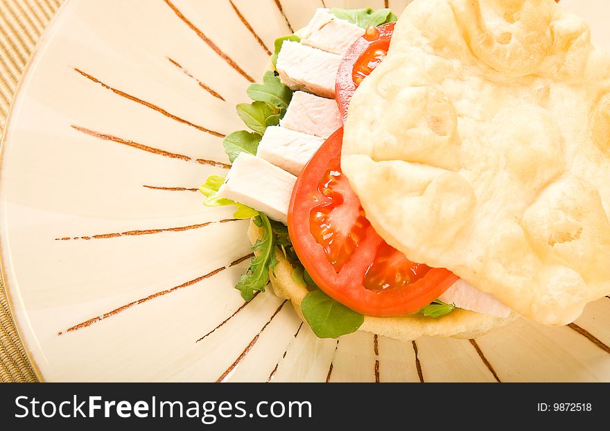 Roasted chicken on buttery flat bread with lettuce and tomato. Roasted chicken on buttery flat bread with lettuce and tomato