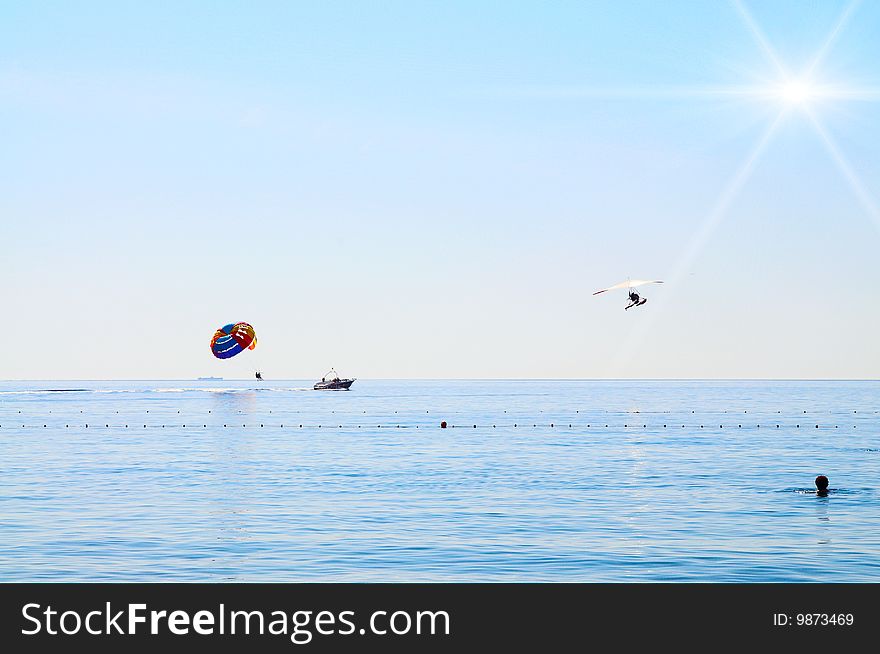 Some man are parasailing over the sea next to seaplane. Some man are parasailing over the sea next to seaplane.