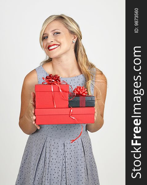 Portrait of a beautiful blonde woman with light blue eyes and evening make-up holding gift boxes on grey background. Portrait of a beautiful blonde woman with light blue eyes and evening make-up holding gift boxes on grey background