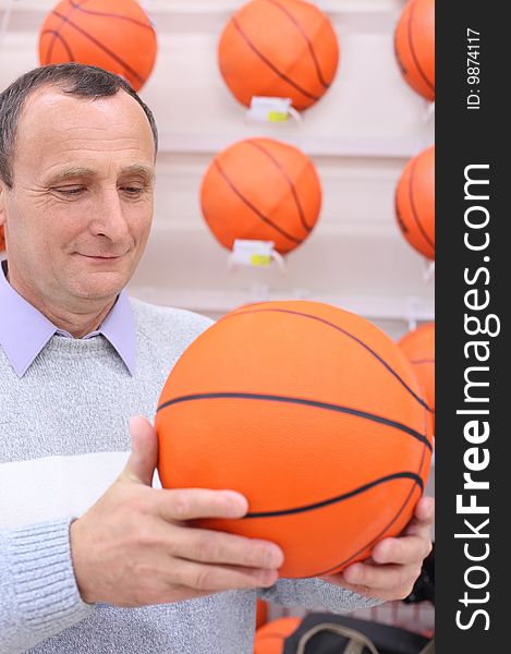 Elderly man in shop with basketball ball in hands. Elderly man in shop with basketball ball in hands