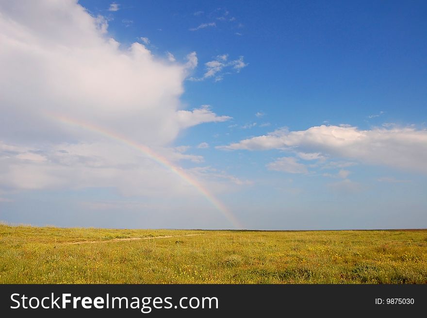 Rainbow in the steppe, blue sky, and white clouds. Rainbow in the steppe, blue sky, and white clouds