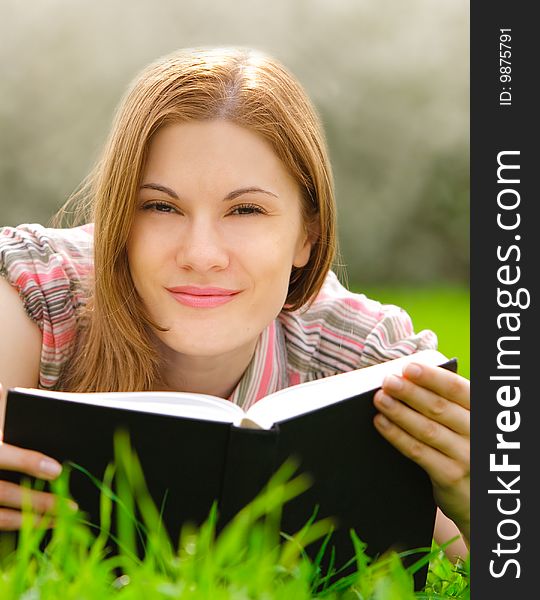 Attractive young woman reading outdoors. Attractive young woman reading outdoors