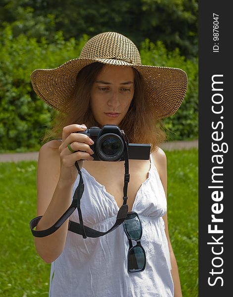 Girl in hat and white skirt looking on digital camera. Girl in hat and white skirt looking on digital camera