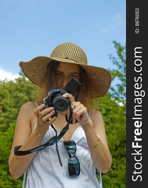 Portrait of a young girl in hat looking on digital camera outdoors. Portrait of a young girl in hat looking on digital camera outdoors