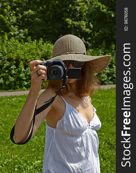 Girl in hat and white skirt holding digital camera in front of her face. Girl in hat and white skirt holding digital camera in front of her face