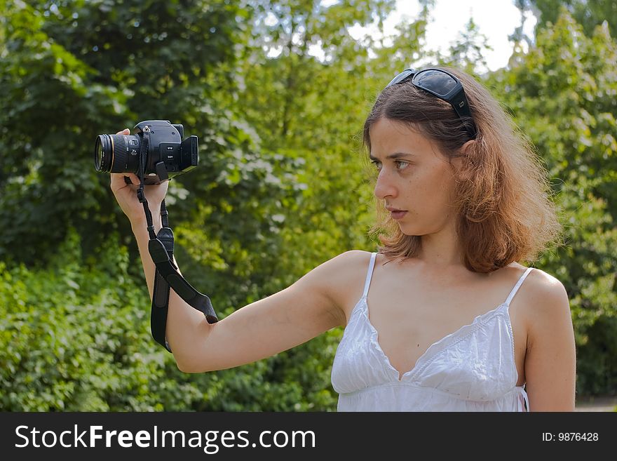 Girl in white skirt holding digital camera on a stretched arm. Girl in white skirt holding digital camera on a stretched arm