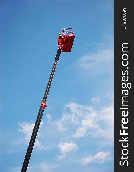 Red hydraulic cherry picker over blue sky