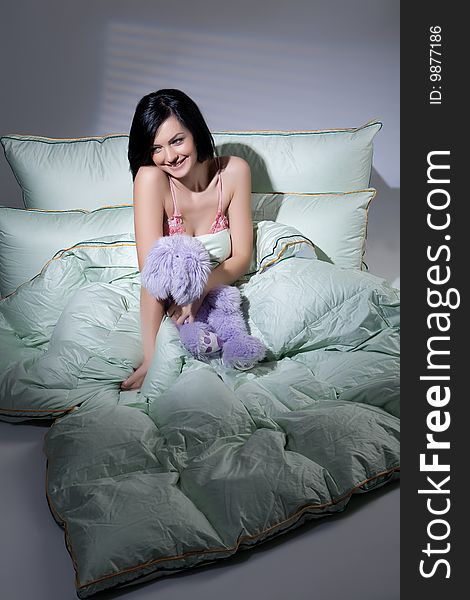 Young beautiful woman lying with down pillows and blanket. Young beautiful woman lying with down pillows and blanket