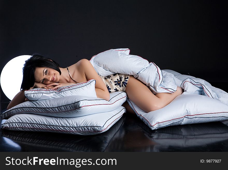 Young beautiful woman lying with down pillows and blanket. Young beautiful woman lying with down pillows and blanket