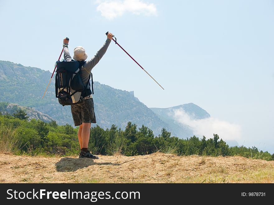 Happy hiker on a peak enjoys a landscape