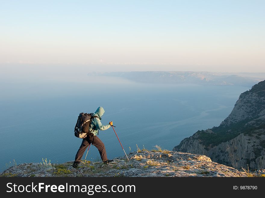 Hiker reaches peak with beautiful view to seashore landscape. Hiker reaches peak with beautiful view to seashore landscape