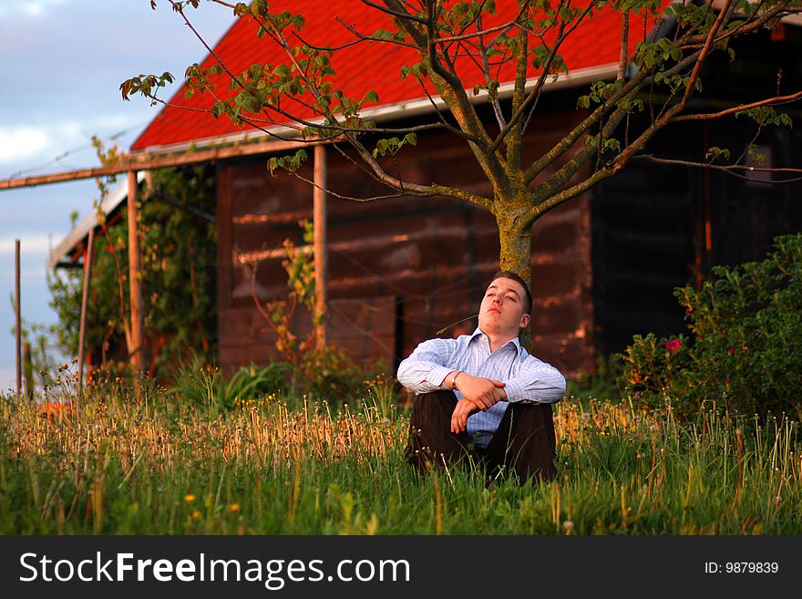 Young man resting by old house watching sunset