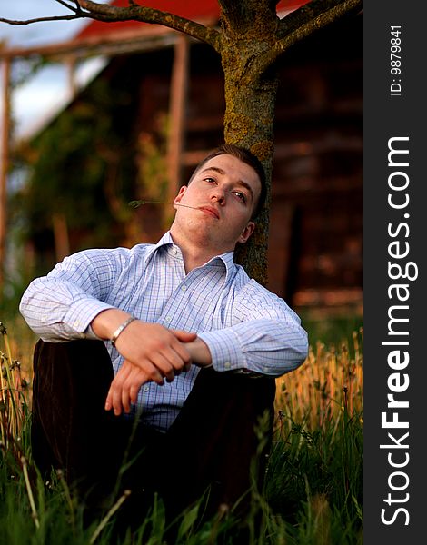 Young man resting by old house watching sunset