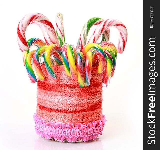 Colored candy in a glass decorated with threads on a white background. Colored candy in a glass decorated with threads on a white background