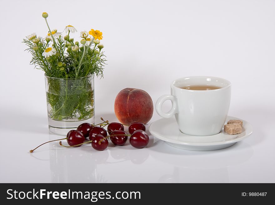 Cup of tea with fruits and horse gowan on white. Cup of tea with fruits and horse gowan on white