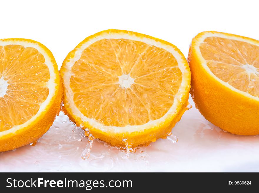 Three halves of oranges with water splash isolated on white background