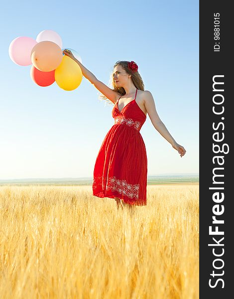 Young woman in a wheat field holding colorful balloons. Young woman in a wheat field holding colorful balloons