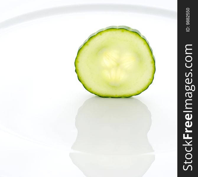 Slice of a cucumber standing on a white plate. Slice of a cucumber standing on a white plate.