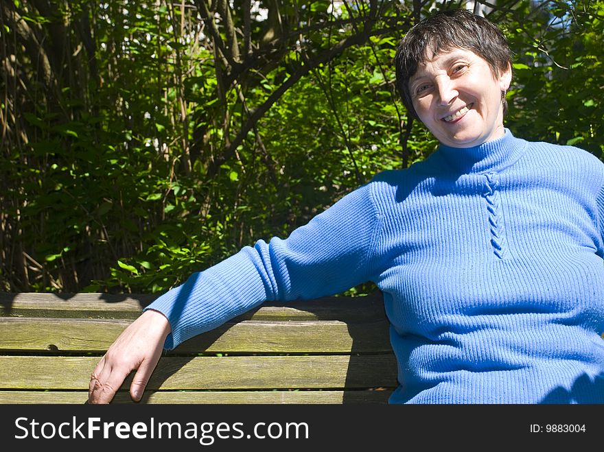 Aged woman sitting in the park and smiling. Aged woman sitting in the park and smiling