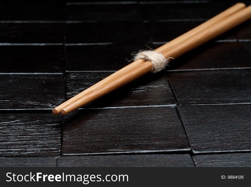 A horizontal closeup  of chopsticks on a black wooden background