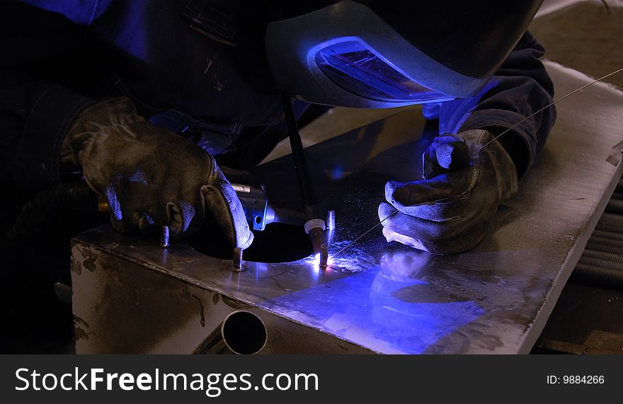 A person welding using TIG on a stainless steel tank. A person welding using TIG on a stainless steel tank