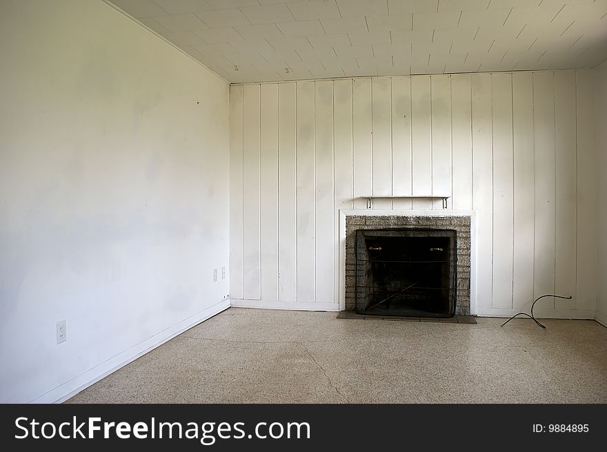 An old abandoned house interior with paneled wall and fireplace in need of repair. An old abandoned house interior with paneled wall and fireplace in need of repair.