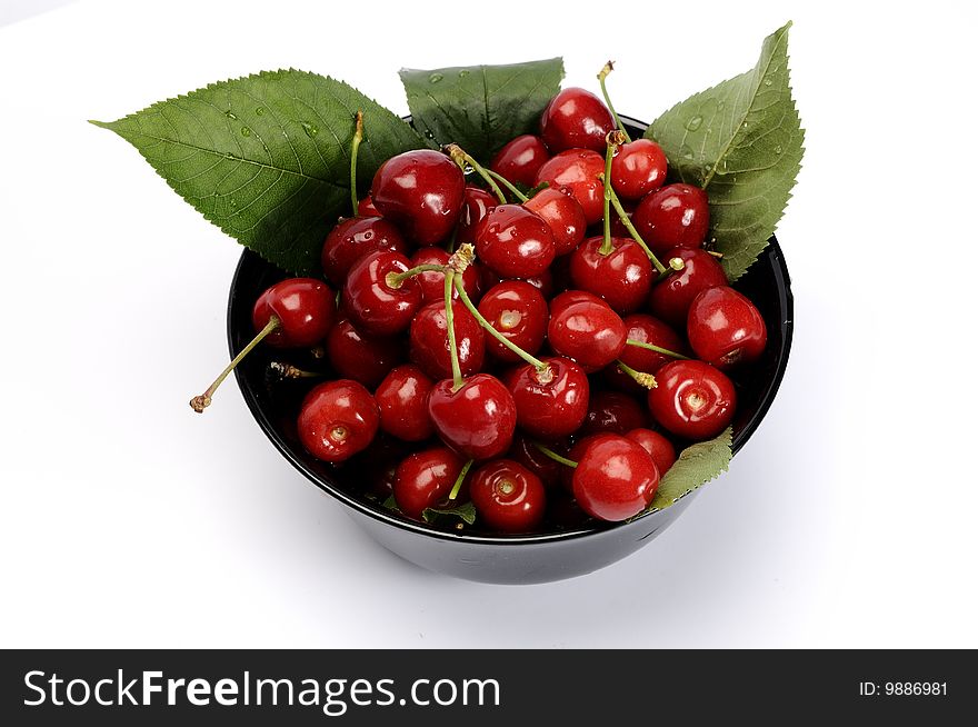 Black bowl with cherries isolated on white. Black bowl with cherries isolated on white