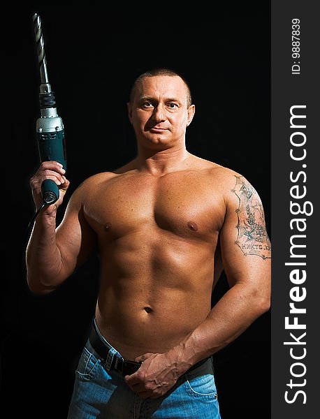 Young strong man with drill on black background. Young strong man with drill on black background