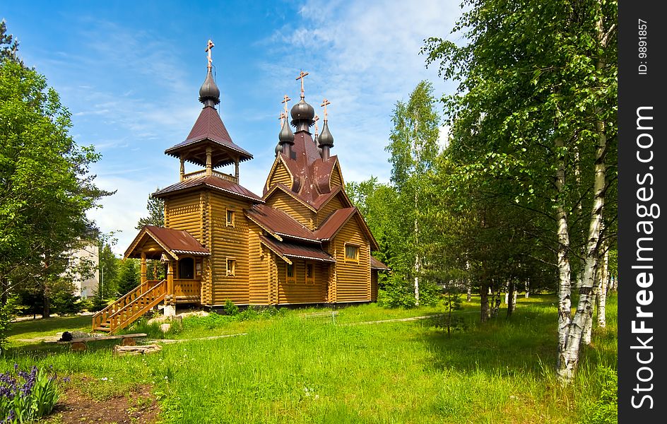 Beautiful wooden church in the village against the backdrop of blue sky and green grass