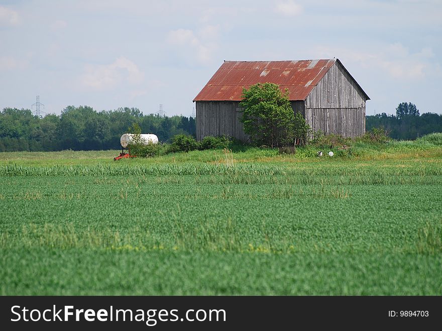 Old barn with water tank in the middle field. Old barn with water tank in the middle field
