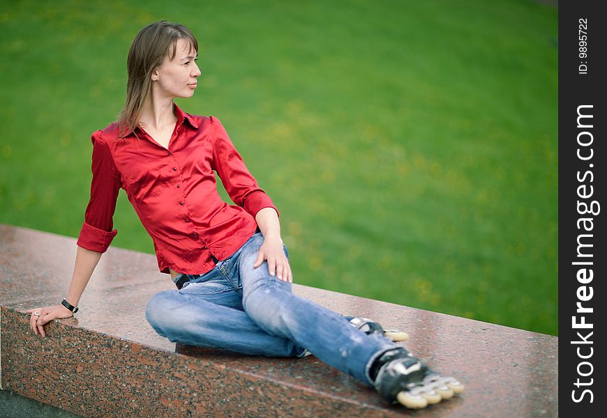 Rollerskating girl in blue jeans sitting on granite plate - shallow DOF