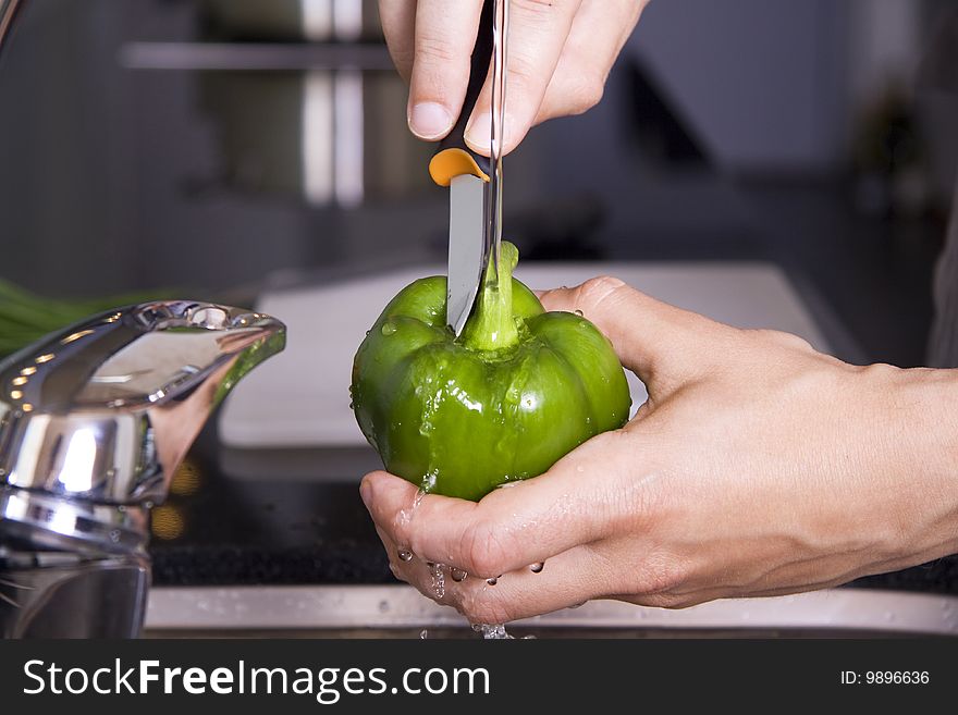 Washing a green pepper in the kitchen sink and cutting out the middle