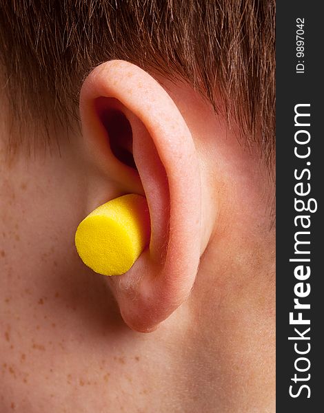 Yellow earplug into the ear close up