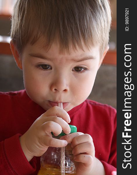 A young boy drinking juice through a straw.