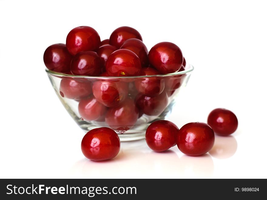 Sour cherries in glass dish before white background.