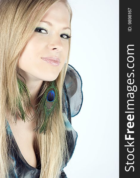 Beautiful young blond model with peacock earrings posing in studio shot. Beautiful young blond model with peacock earrings posing in studio shot