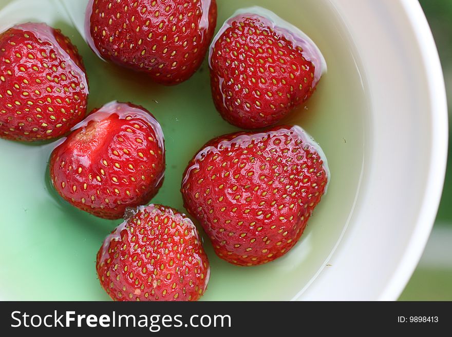 Red strawberries in green jelly, served in white bowl