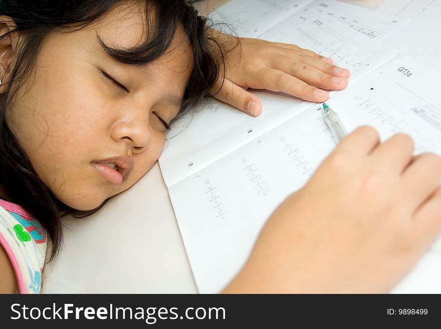 Asian elementary school girl fall a sleep on the table while doing math homework, seems exhausted. Asian elementary school girl fall a sleep on the table while doing math homework, seems exhausted.