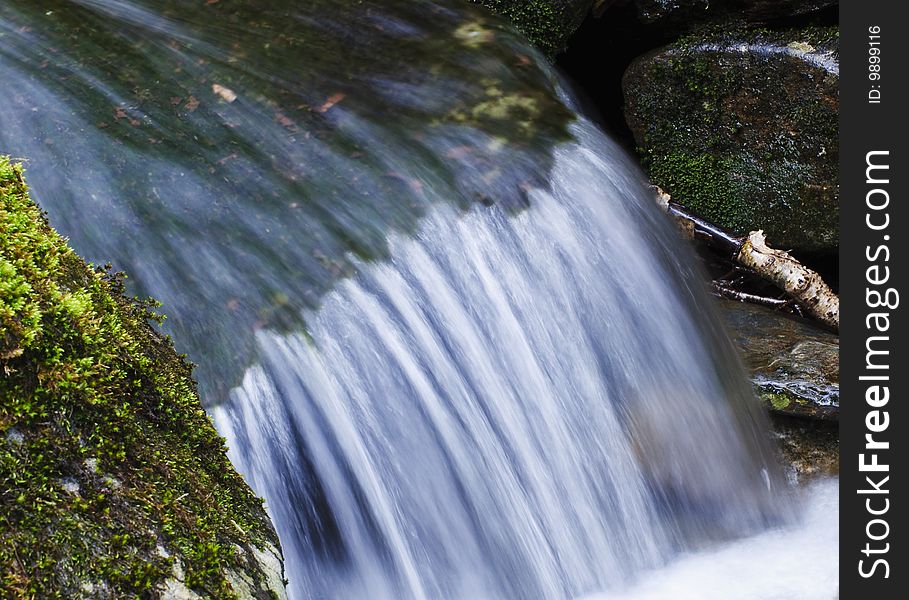 Close up of waterfall flowing over mossy rock. Close up of waterfall flowing over mossy rock