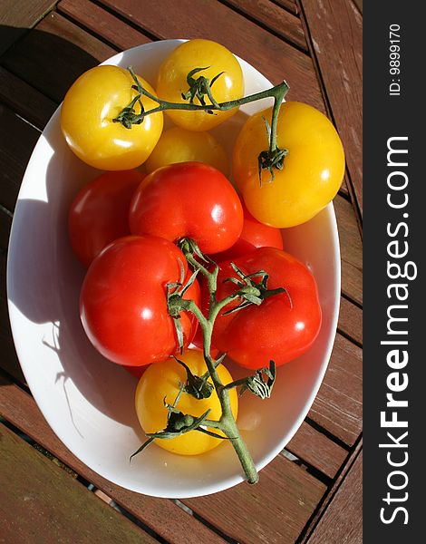 Red and yellow tomatoes in the vase, look fresh an juicy, organic ones