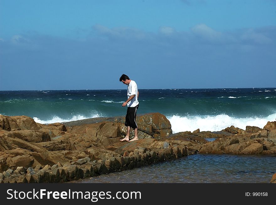 Man walking on the rocks at the beach. Man walking on the rocks at the beach