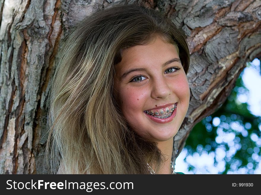 Pretty teenage girl with braces smiling in front of a tree. Pretty teenage girl with braces smiling in front of a tree.