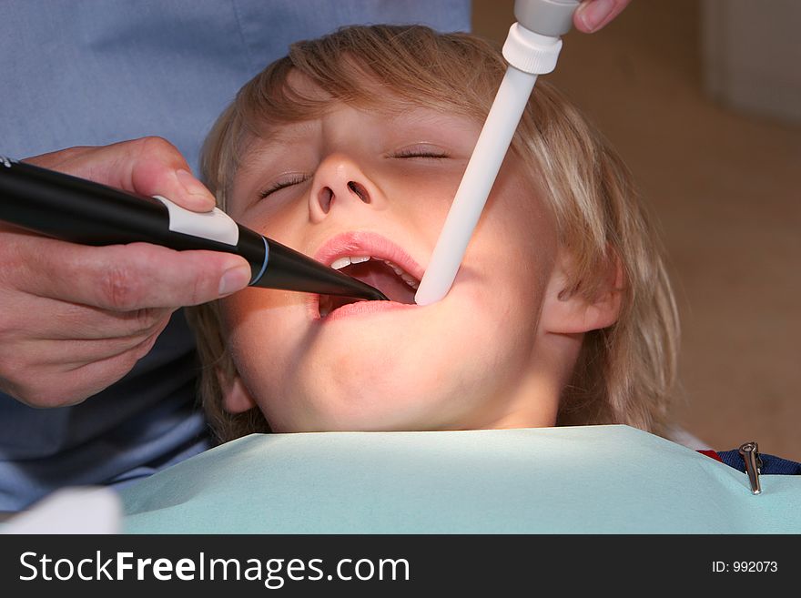 A young boy at the dentists, dentist taking a look into his mouth using various tools. A young boy at the dentists, dentist taking a look into his mouth using various tools