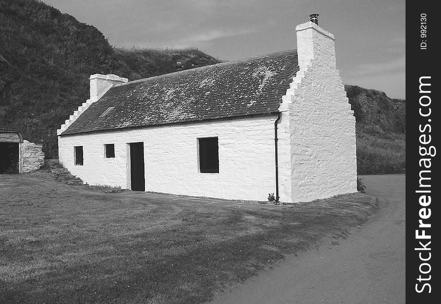 An old fishermans cottage on the harbour edge nestling into the cliff. An old fishermans cottage on the harbour edge nestling into the cliff.