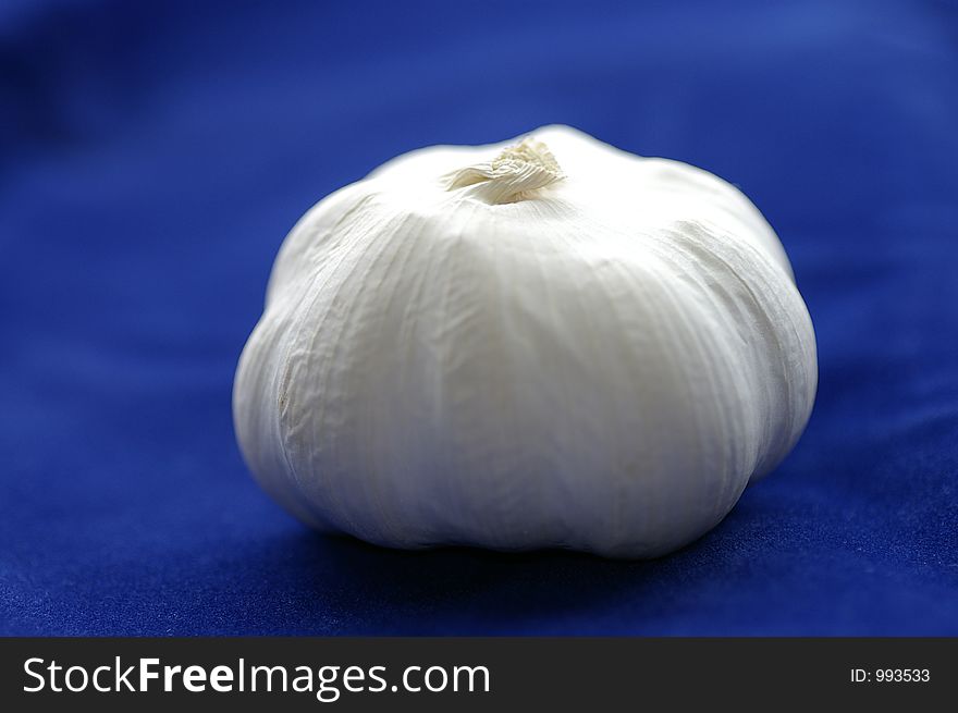 Closeup of a garlic bulb against a blue background. Closeup of a garlic bulb against a blue background